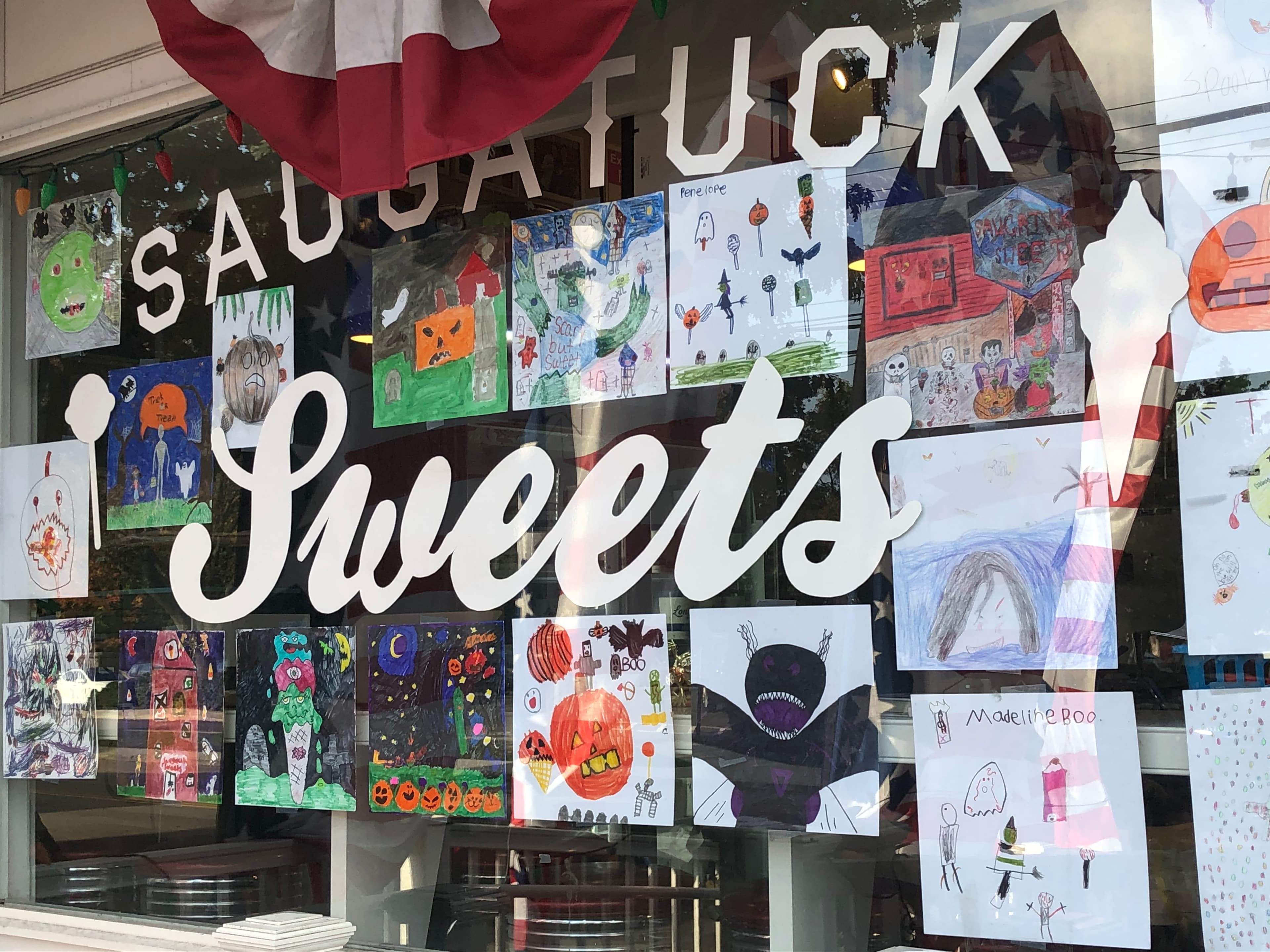 The Saugatuck Sweets storefront window covered in kids' Halloween artwork